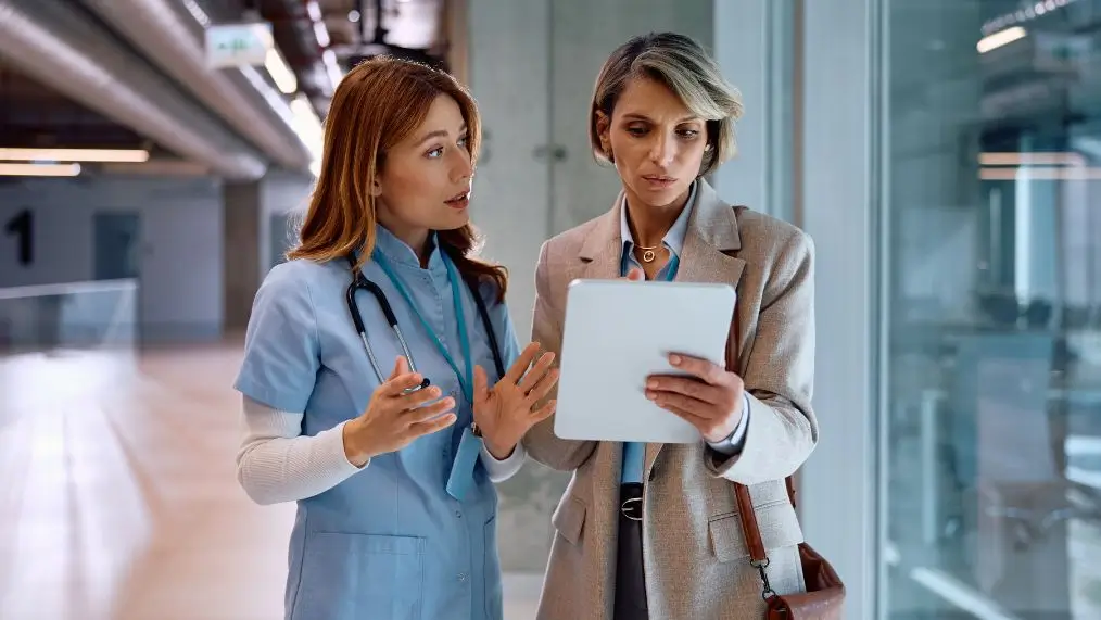 Healthcare office worker and administrator reviewing digital documents on tablet