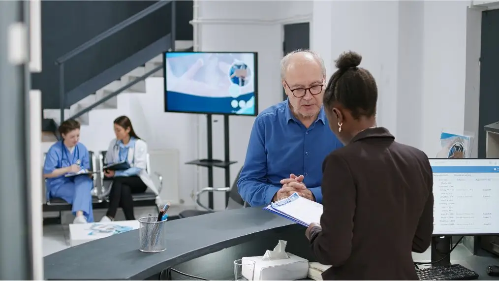 medical receptionist helping patient at front desk