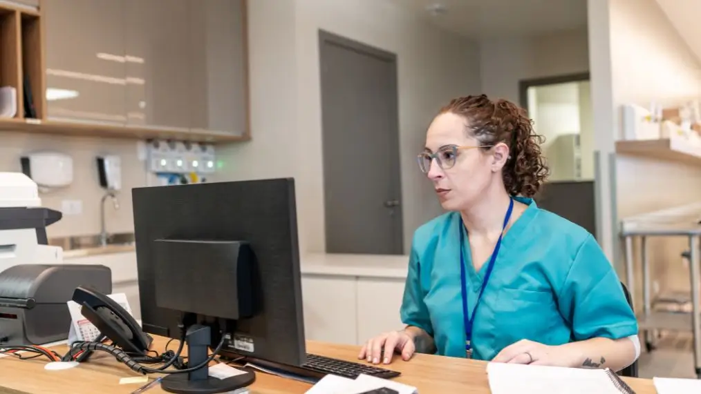 Woman in scrubs working at computer